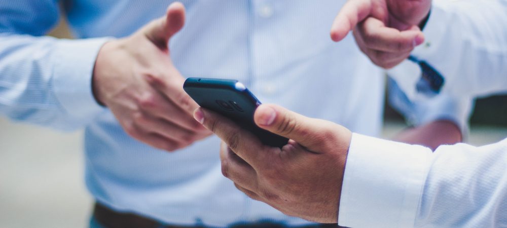 Men halding a smartphone and pointing to FieldVibe's free scheduling app for field service professionals